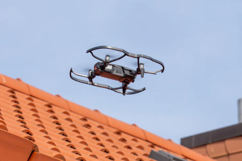Dachinspektionen mit Drohne: Drohne über dem Ziegeldach eines Wohnhauses